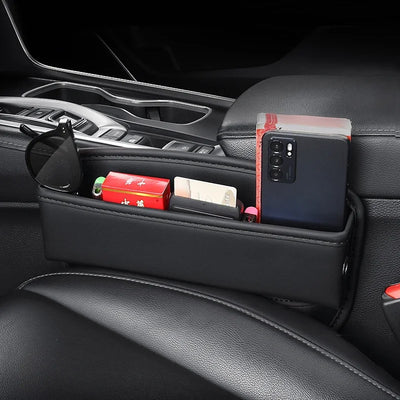 Black PU leather car seat crevice storage box organizer holding phone, sunglasses, and small items between car seat and console